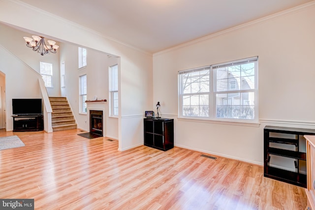 interior space featuring visible vents, ornamental molding, a fireplace with flush hearth, and light wood-style flooring