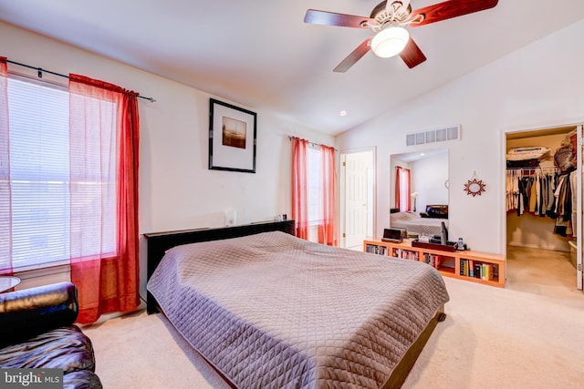 bedroom with lofted ceiling, light colored carpet, a ceiling fan, visible vents, and a walk in closet