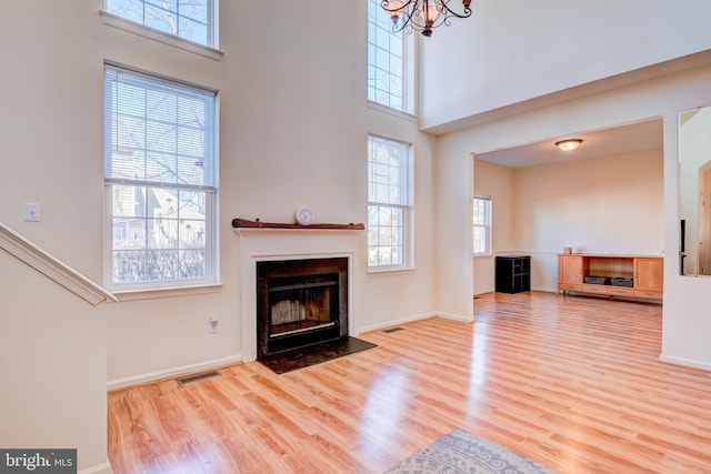 living room featuring plenty of natural light, light wood finished floors, a fireplace with flush hearth, and visible vents