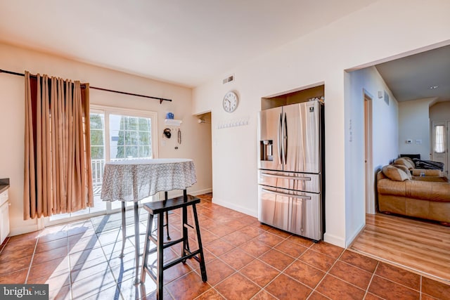 kitchen featuring baseboards, visible vents, white cabinets, stainless steel fridge with ice dispenser, and tile patterned floors