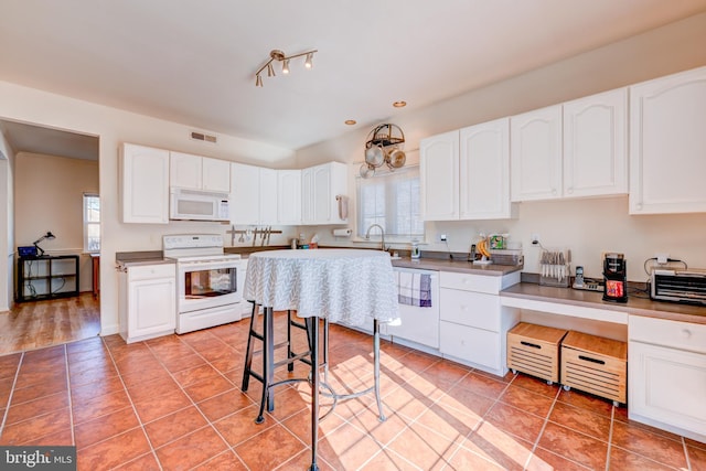 kitchen featuring white appliances, white cabinets, a sink, and light tile patterned flooring