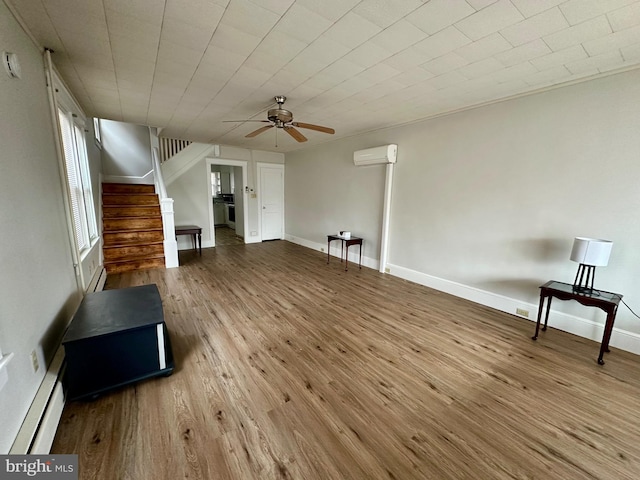 unfurnished living room featuring baseboard heating, ceiling fan, light hardwood / wood-style floors, and a wall mounted AC