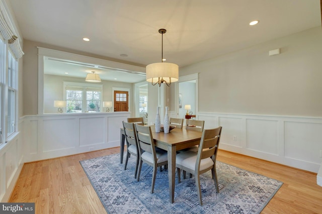 dining room featuring light wood-type flooring, wainscoting, a decorative wall, and recessed lighting