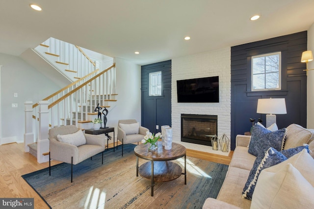 living area with stairs, recessed lighting, a fireplace, and wood finished floors