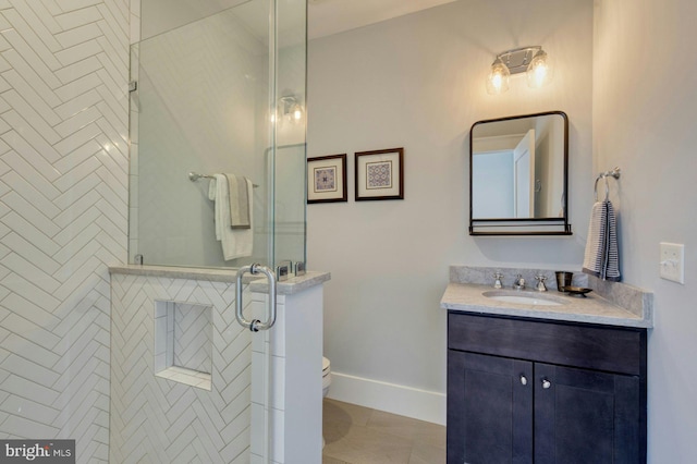 bathroom with toilet, vanity, baseboards, tile patterned floors, and a stall shower