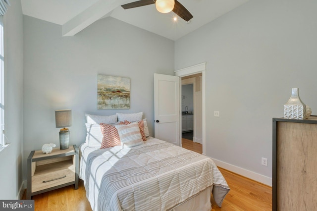 bedroom featuring baseboards, vaulted ceiling, a sink, and light wood-style floors