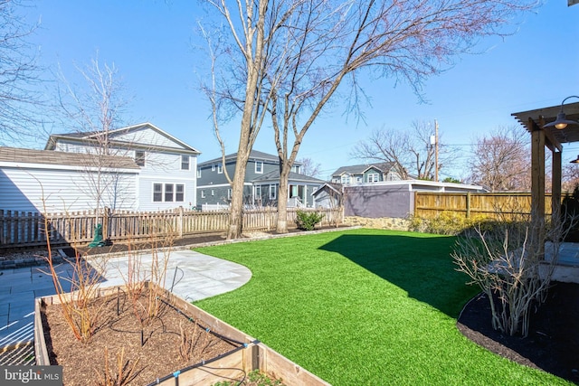 view of yard with a garden, a patio area, a fenced backyard, and a residential view