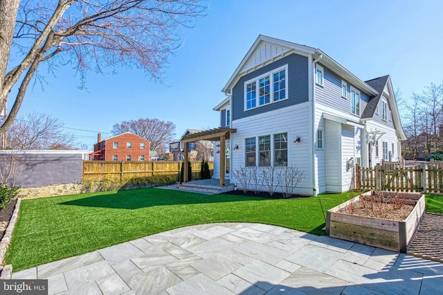 rear view of property with a garden, fence, a yard, a patio area, and board and batten siding