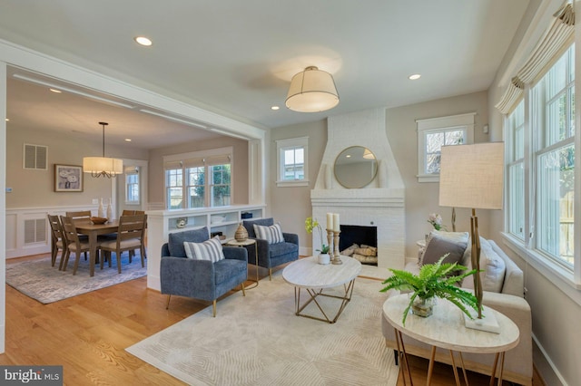 living room featuring a healthy amount of sunlight, visible vents, a fireplace, and wood finished floors