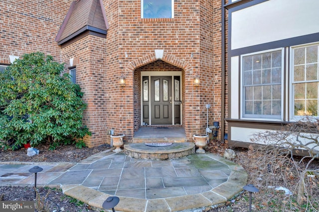 property entrance with a patio area and brick siding