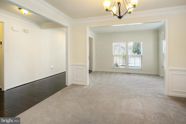 unfurnished room with an inviting chandelier, a wainscoted wall, ornamental molding, and light carpet