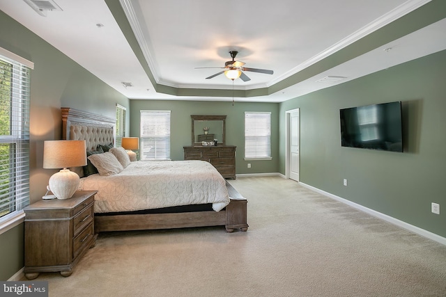 bedroom featuring light colored carpet, a raised ceiling, ornamental molding, and baseboards