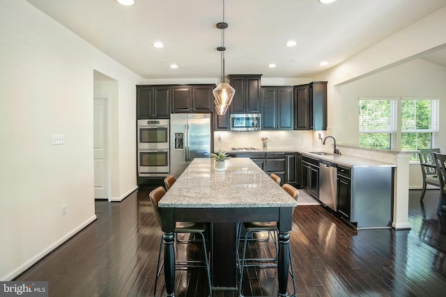 kitchen with light stone countertops, a sink, stainless steel appliances, and dark wood-type flooring