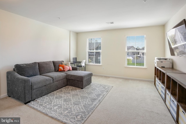 living area featuring visible vents, light carpet, and baseboards