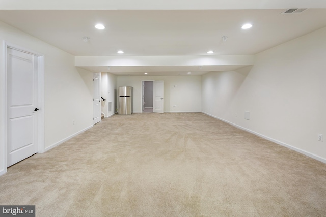 finished below grade area with baseboards, recessed lighting, light carpet, and freestanding refrigerator