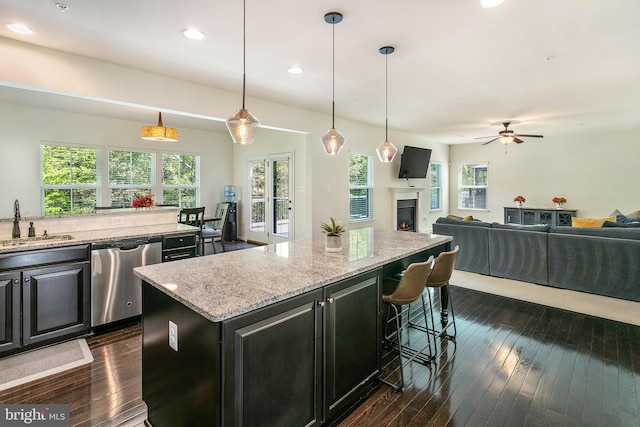 kitchen with a kitchen island, dishwasher, a sink, a ceiling fan, and dark wood-type flooring