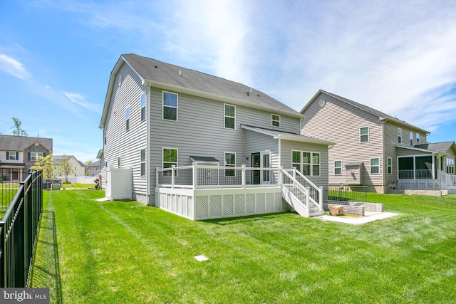 back of house featuring a lawn, a wooden deck, and fence
