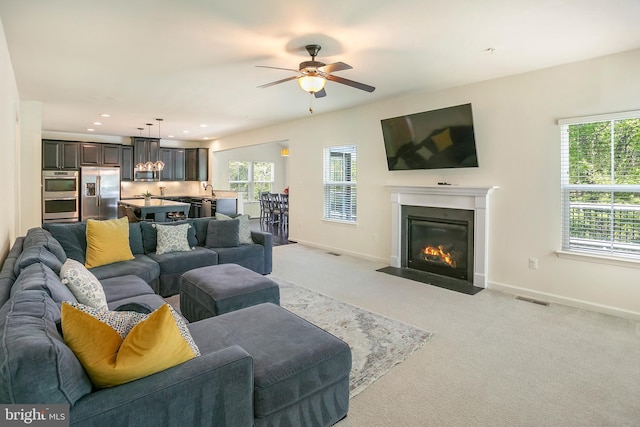 living room with visible vents, plenty of natural light, a ceiling fan, and baseboards