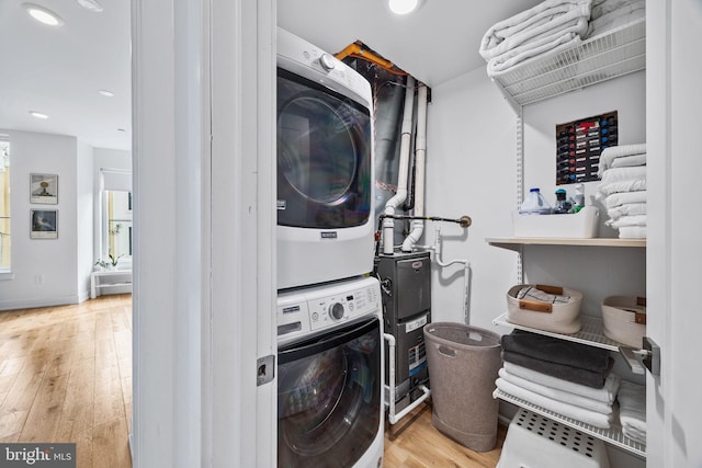 washroom with stacked washer and dryer and light hardwood / wood-style flooring