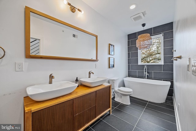 bathroom with tile walls, vanity, a bathing tub, tile patterned flooring, and toilet