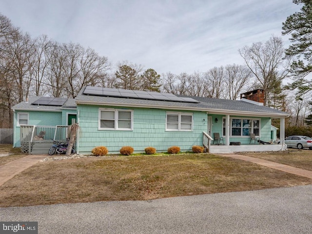 ranch-style house with solar panels, a front lawn, and a porch