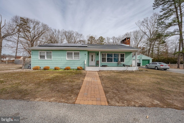 ranch-style home with solar panels, a porch, a front yard, and a garage