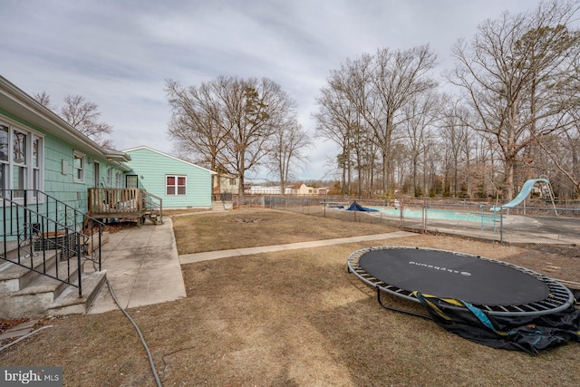 view of yard featuring a trampoline and a fenced in pool