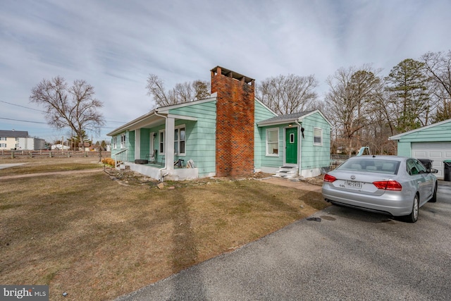 view of front facade with a garage, a front lawn, an outbuilding, and a porch