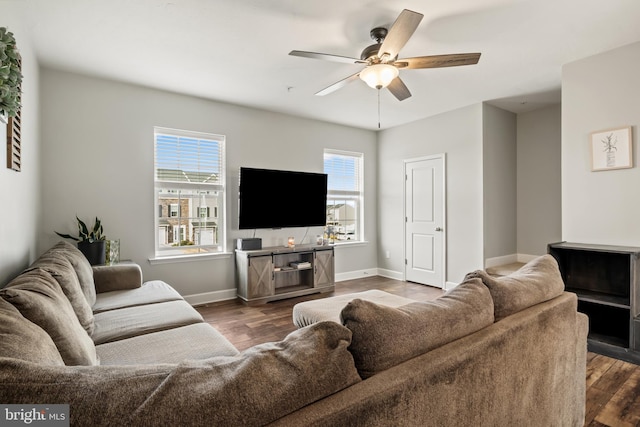 living area with baseboards, a ceiling fan, and wood finished floors