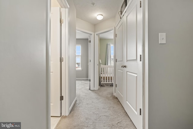 corridor with light colored carpet and baseboards