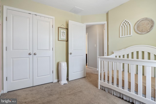 carpeted bedroom featuring a closet, baseboards, and a crib