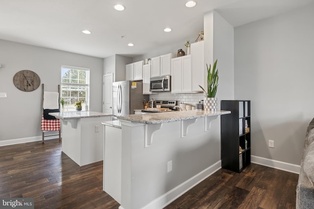 kitchen with backsplash, a peninsula, stainless steel appliances, and a kitchen breakfast bar