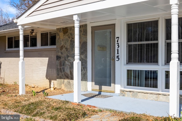 property entrance featuring brick siding and roof with shingles