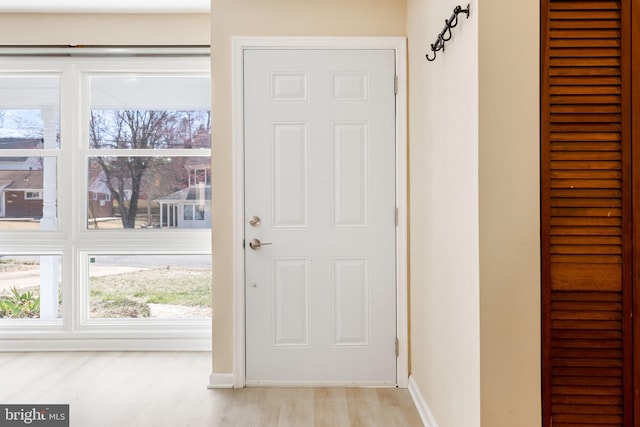 doorway featuring baseboards and light wood finished floors