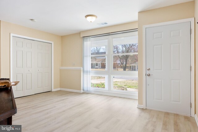 foyer entrance featuring visible vents, a healthy amount of sunlight, baseboards, and wood finished floors