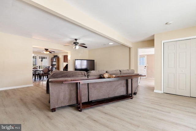 living room with light wood-type flooring, baseboards, and beam ceiling