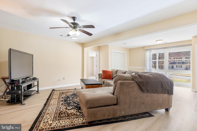 living area featuring baseboards, light wood-style flooring, and a ceiling fan