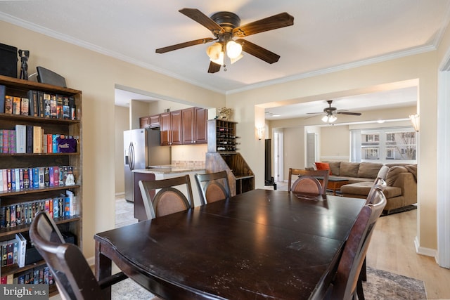 dining room featuring ceiling fan, baseboards, ornamental molding, and light wood finished floors