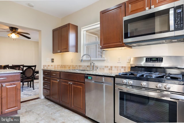 kitchen featuring a sink, light stone counters, and stainless steel appliances