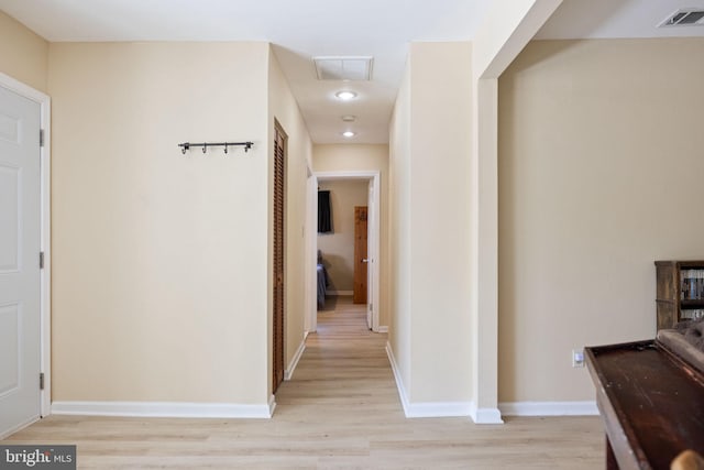 hall featuring light wood finished floors, visible vents, and baseboards