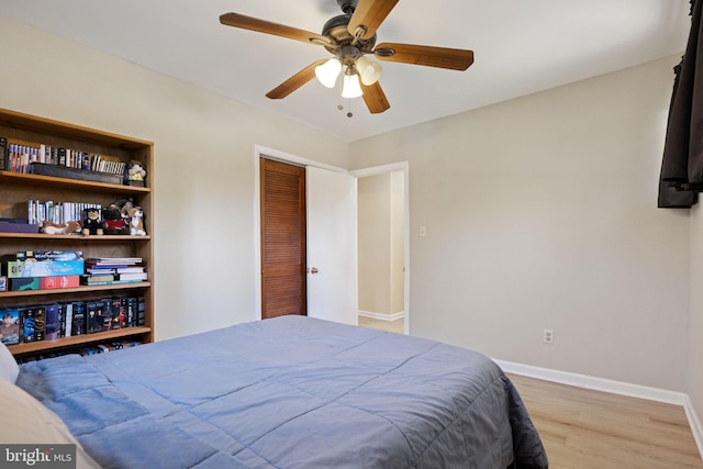 bedroom featuring a closet, baseboards, wood finished floors, and a ceiling fan