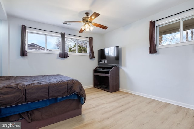 bedroom featuring visible vents, a ceiling fan, baseboards, and wood finished floors