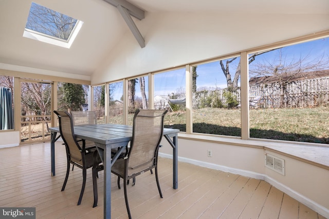 sunroom featuring visible vents, vaulted ceiling with skylight, and a healthy amount of sunlight