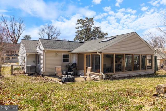 back of house with a shingled roof, fence, central air condition unit, a lawn, and a sunroom