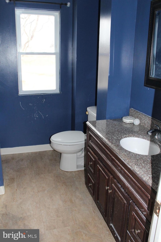 bathroom featuring baseboards, vanity, and toilet