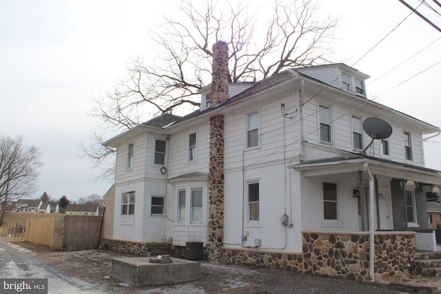 view of home's exterior with brick siding, covered porch, and fence