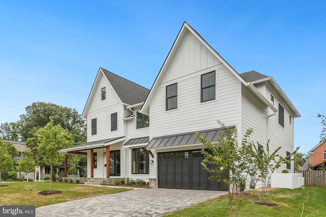 modern farmhouse featuring metal roof, a standing seam roof, decorative driveway, a front lawn, and board and batten siding