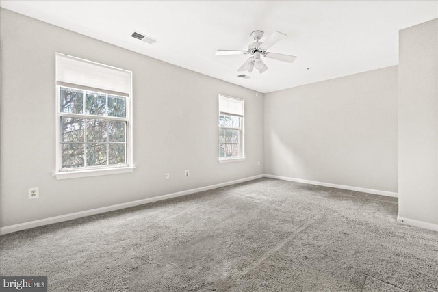 carpeted spare room featuring ceiling fan, visible vents, and baseboards