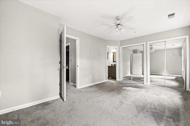 unfurnished bedroom with carpet, multiple closets, visible vents, ensuite bathroom, and baseboards