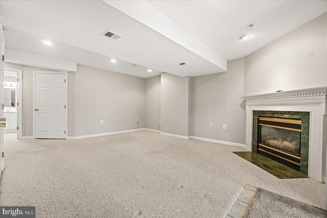 unfurnished living room featuring carpet, a high end fireplace, visible vents, and baseboards